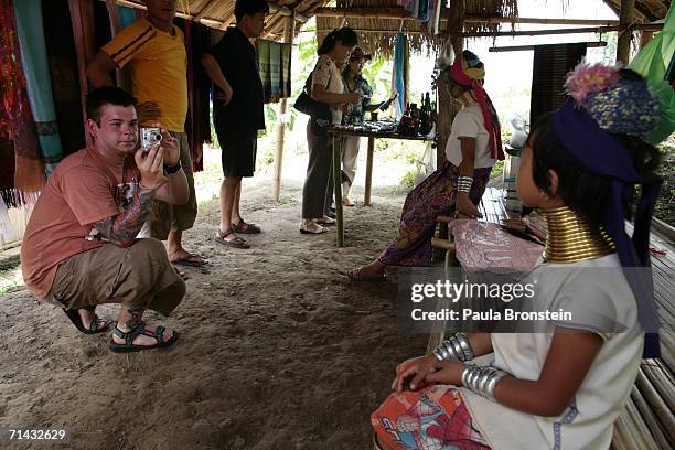 Foreign tourist takes a photo of a young Long Neck Padaung hill tribe girl at a handicrafts stall in a small village where 30 familes live July 13,...