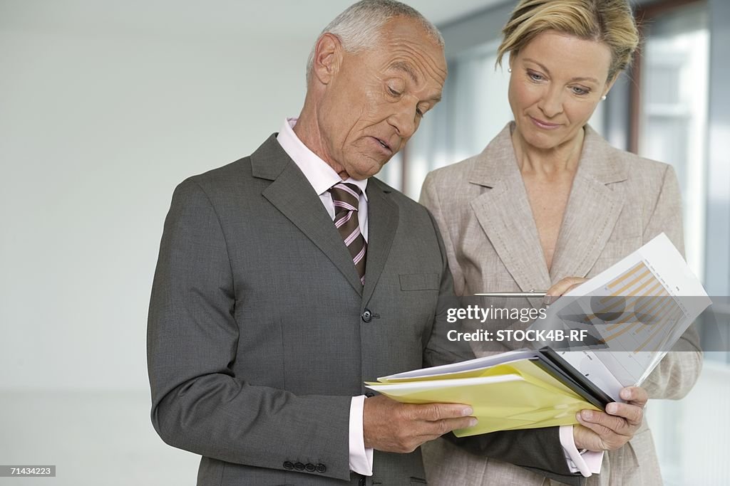 Elderly manager with blond business woman studying business papers