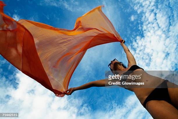 woman holding a orange colored fabric in the tropical breeze on the island of barbados, caribbean - flasher photos et images de collection