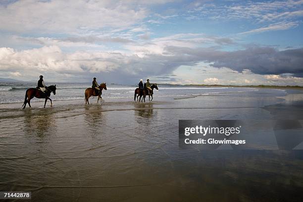 four people horseback riding on the beach, sligo, republic of ireland - sligo stock pictures, royalty-free photos & images