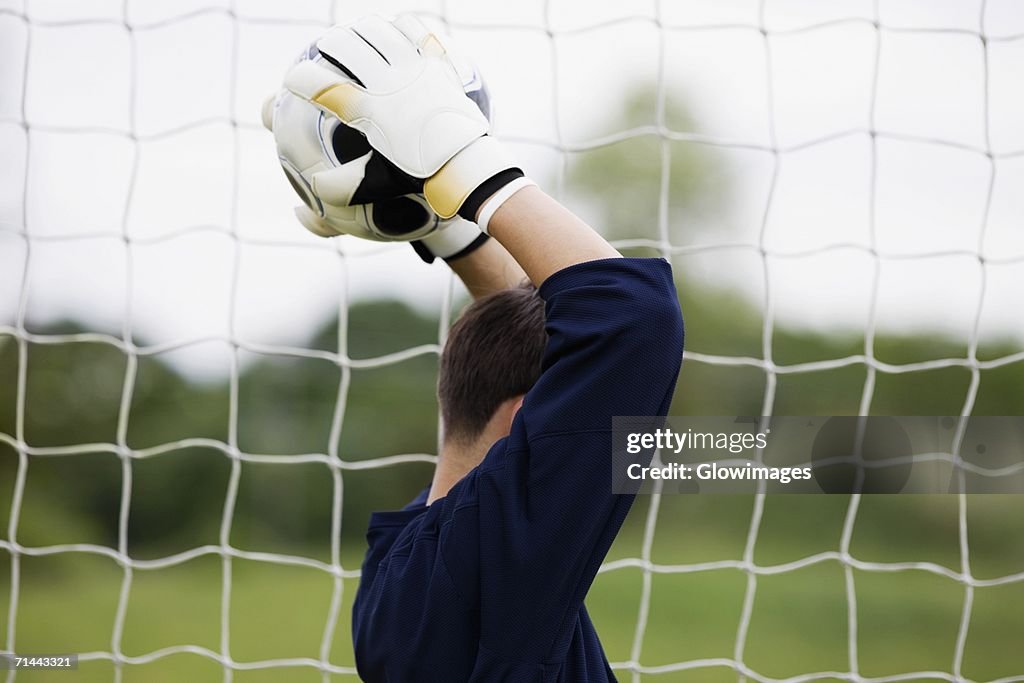 Side profile of a goalie holding a soccer ball over his head