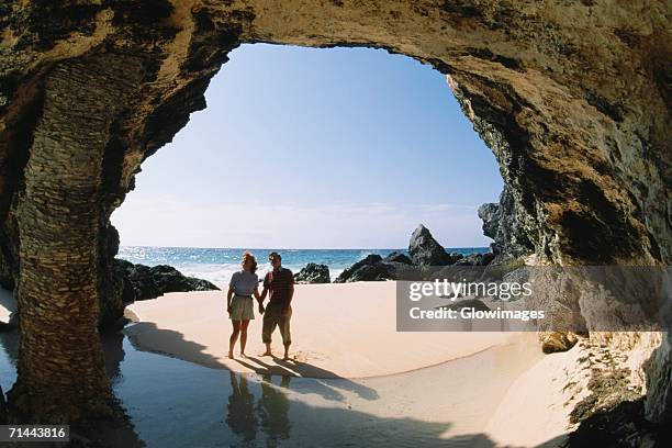 a couple observing rocks near the ocean, natural arch, bermuda - bermuda beach stockfoto's en -beelden