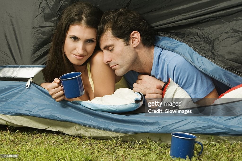 Close-up of a young woman and a mid adult man lying in a tent