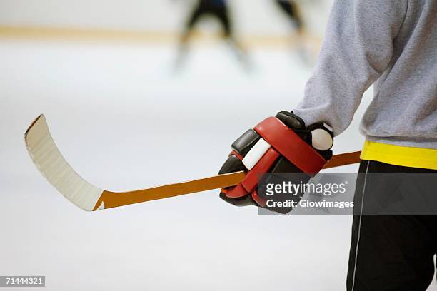 mid section view of an ice hockey player holding an ice hockey stick - guante de hockey sobre hielo fotografías e imágenes de stock