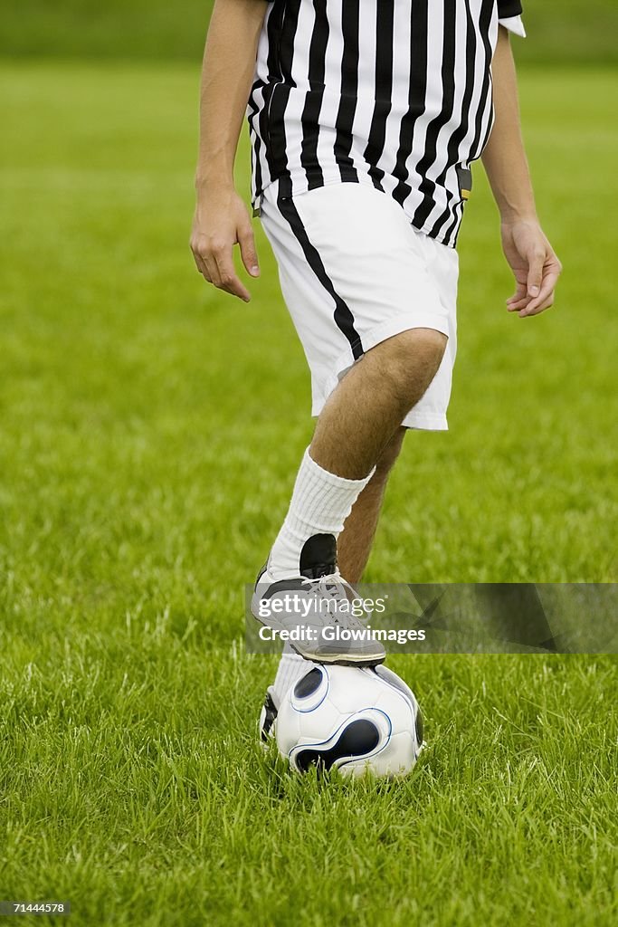 Low section view of a soccer player resting his foot on a soccer ball