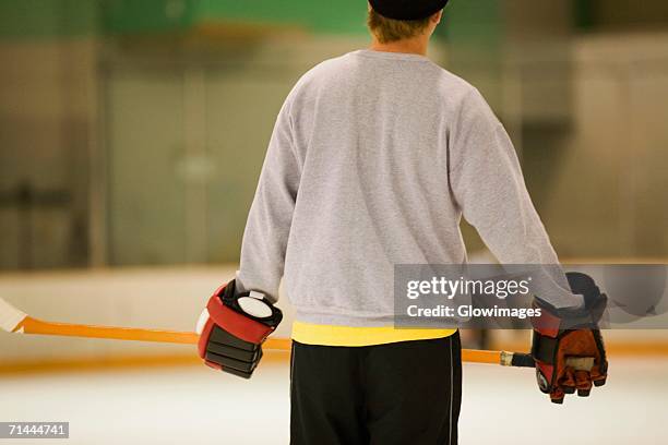 rear view of an ice hockey player holding an ice hockey stick - ice hockey player back turned stock pictures, royalty-free photos & images