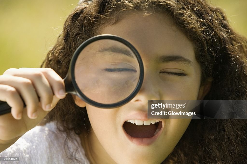 Close-up of a girl looking through a magnifying glass