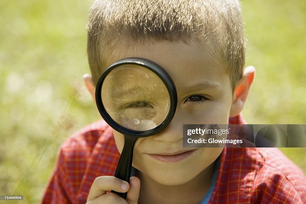 Portrait of a boy looking through a magnifying glass