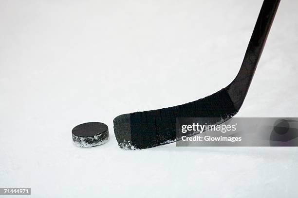 close-up of an ice hockey stick with a hockey puck - eishockey schläger stock-fotos und bilder