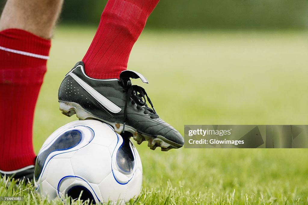 Close-up of a person's foot resting on a soccer ball