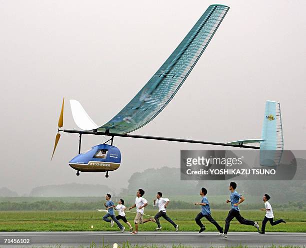 The world's first one-seater dry-battery powered aircraft soars in the air, while students of the Tokyo Institute of Technology follow it, at the...