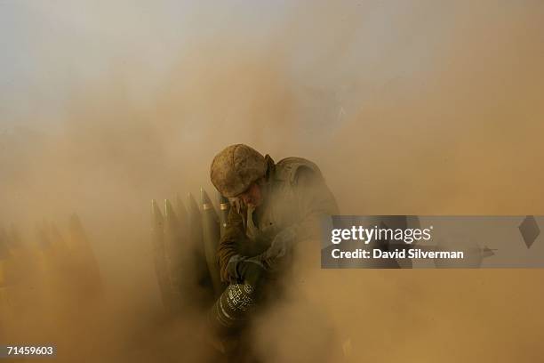 An Israeli soldier is surrounded with dust kicked up by a 155mm artillery cannon as it opens fire during a barrage against Hezbollah targets in South...