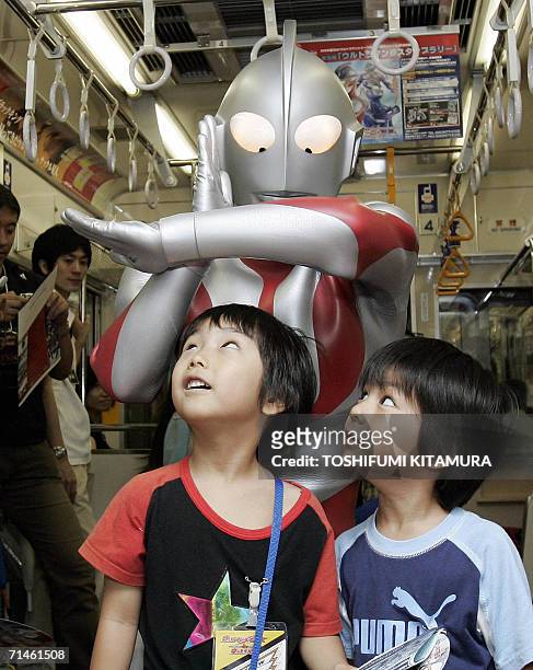 Ultraman Jack poses with young fans during a press preview inside a train in Tokyo, 17 July 2006. The event was held to commemorate the 40th...