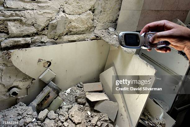 An Israeli policeman uses his cell phone to photograph a Katyusha rocket which struck an apartment building, damaging two apartments and leaving the...