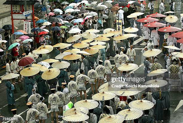 People hold umbrellas during the Gion Festival July 17, 2006 in Kyoto, Japan. The traditional festival started in 869 AD after a plague spread...