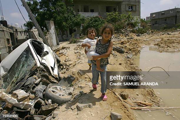 Palestinian girl carries a baby as she walks past cars, broken water pipes and churned up earth in a neighborhood of Beit Hanun, in northern Gaza...