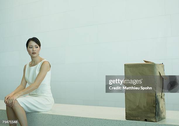 woman sitting on bench looking at suspicious package - suspicious package stock pictures, royalty-free photos & images