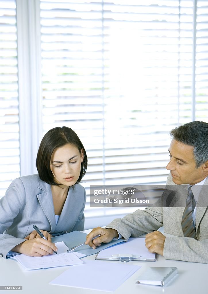 Two business associates discussing documents at desk