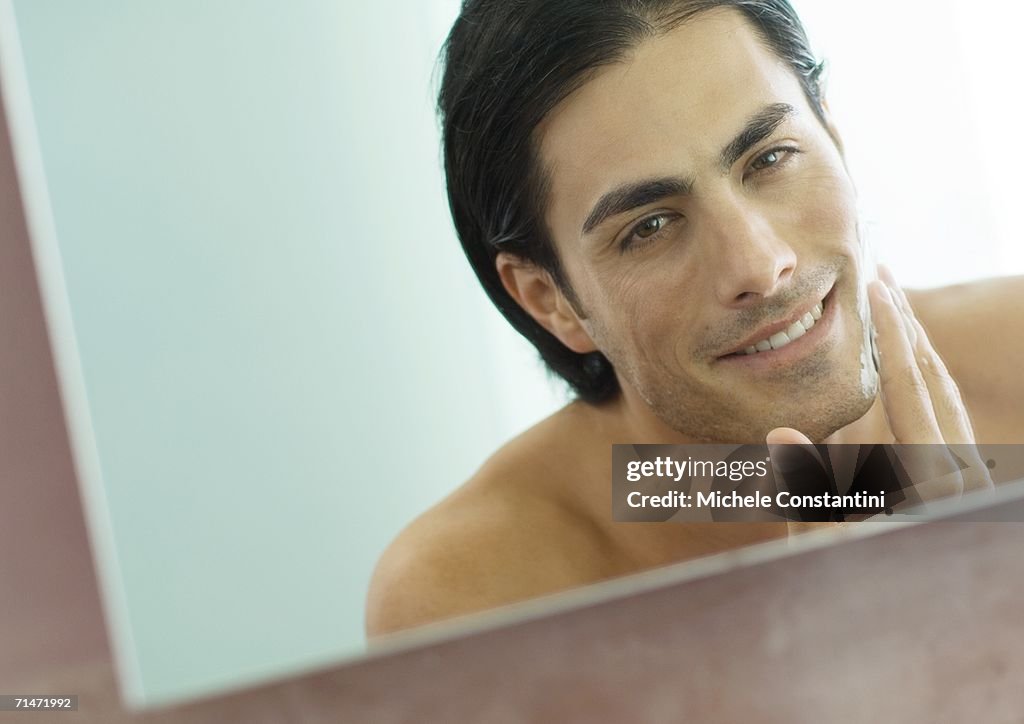 Man applying shaving cream in mirror