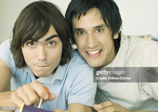 two young men playing video game - sólo hombres jóvenes fotografías e imágenes de stock