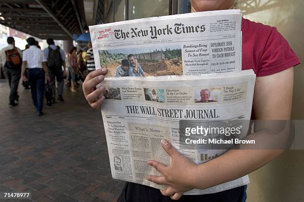 Woman sells copies of The New York Times and The Wall Street Journal newspapers outside the Port Authority Bus Terminal July 18, 2006 in New York...