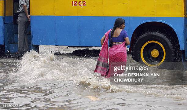 An Indian woman waits to board a bus at a water-logged street in Kolkata, 19 July 2006. Life was badly disrupted in the eastern Indian city after a...