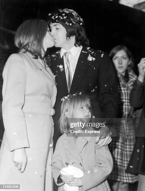 Paul McCartney kissing his bride Linda during their wedding at Marylebone registry office. Linda's daughter Heather stands with them, 12th March 1969.