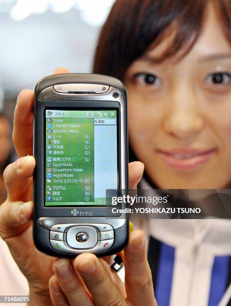 An employee of Japan's mobile communication giant NTT DoCoMo displays the new PDA shaped mobile handset "htc Z", produced by Taiwanese maker...