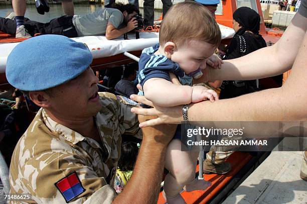 Staff hands a young boy to a colleague as foreign nationals board a Cypriot vessel in the southern Lebanese port city of Tyre 20 July 2006 in order...