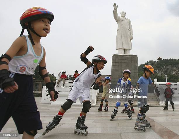 Children play roller skating in front of a statue of former Chinese leader Mao Zedong on July 17, 2006 in Tangshan of Hebei Province, China. July 28...