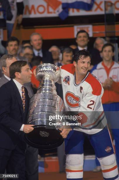 Canadian professional hockey player Guy Carbonneau , center for the Montreal Canadiens, accepts the Stanley Cup from American NHL commissioner Gary...