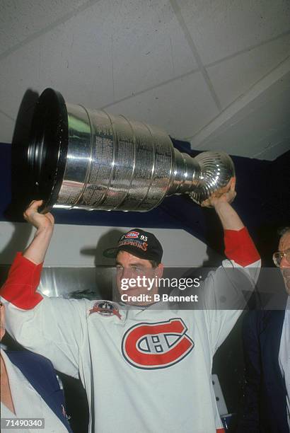 American professional hockey player John Leclair, left wing for the Montreal Canadiens, hoists the Stanley Cup over his head as he celebrates their...