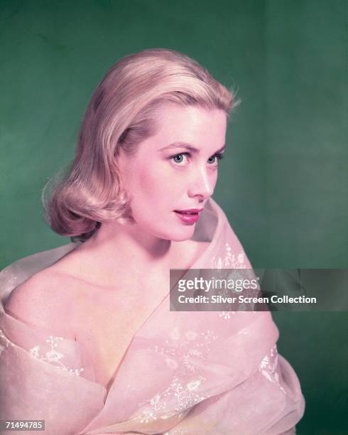 American actress Grace Kelly in a pink wrap, circa 1955.