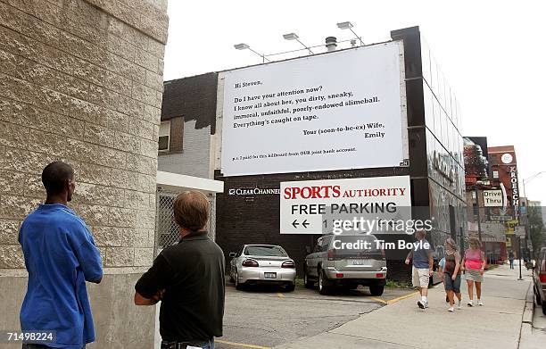 Passersby look at a billboard claimingto be from an unhappy wife railing against her husband's infidelity July 21, 2006 in Chicago, Illinois. Some...