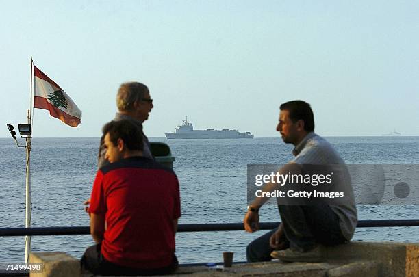 Lebanese men sit and chat on Beirut harbour as American families are evacuated by a U.S. Marine helicopter ship in the Mediterranean Sea on July 21,...