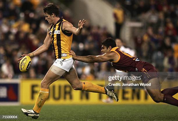 Robert Campbell of Hawthorn successfully kicks for goal despite an attempted tackle by Mal Michael of the Lions during the round 16 AFL match between...