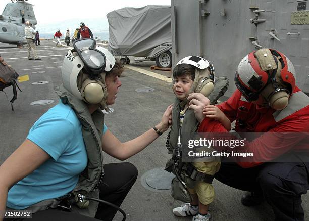In this handout photo provided by the U.S. Navy, a woman comforts a small child after arriving aboard the amphibious transport dock USS Trenton by...