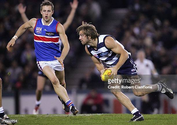 Joel Corey of the Cats gets away from Daniel Cross of the Bulldogs during the round 16 AFL match between the Geelong Cats and the Western Bulldogs at...