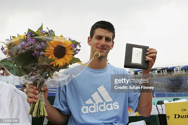 Novak Djokovic of Serbia & Montenegro celebrates defeating Nicolas Massu of Chile in straight sets with his prize - an ipod and some flowers after...