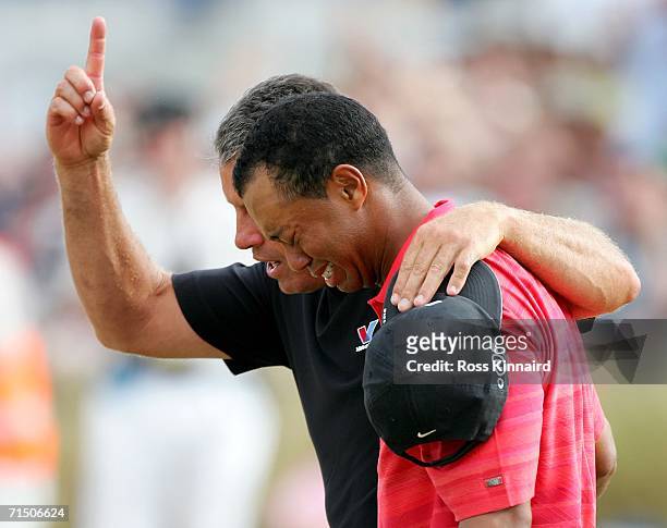 Tiger Woods of USA walks off the 18th green in tears with his caddy Steve Williams following his victory at the end of the final round of The Open...