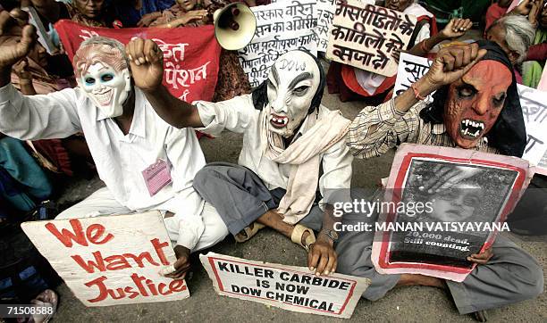 Indian victims of the 1984 Bhopal gas tragedy wear masks as they shout anti-government and anti-Union Carbide slogans during a protest in New Delhi,...