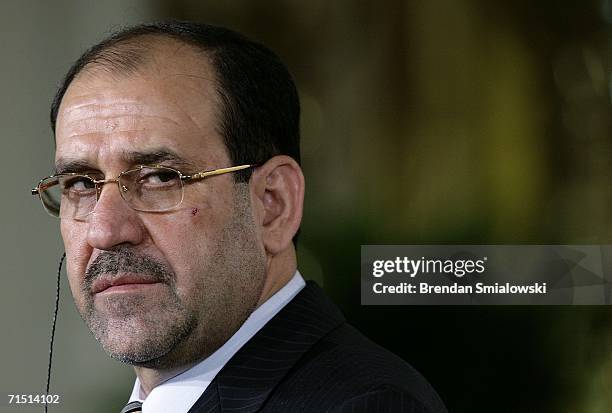 Iraq's Prime Minister Nuri al-Maliki listens as U.S. President George W. Bush speaks during a joint press conference at the White House July 25, 2006...