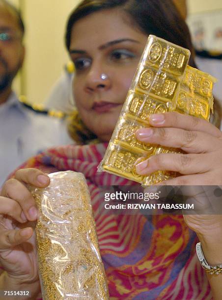 Pakistani female custom official shows seized packets of gold and jewelry during a press conference in Karachi, 25 July 2006. Pakistani custom...