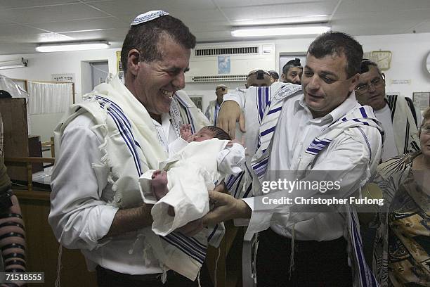 Shalom Hen hands his eight-day-old son Ofir Hen to his godfather during a circumcision ceremony by the local Rabbi inside a bomb shelter on July 26,...