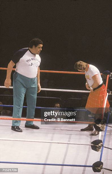 French professional wrestler and actor Andre the Giant , in the ring as a special guest referee, looks on as Rowdy Roddy Piper adjusts his kilt...