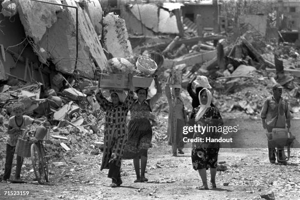 In this archive image provided by the Israeli Government Press Office , Lebanese women pass the ruins of a destroyed militants' outpost during...