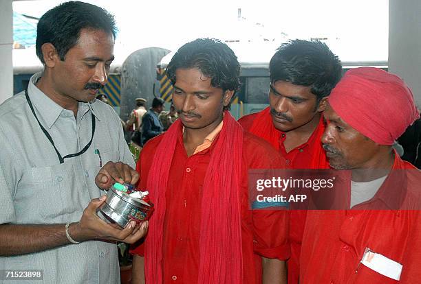 An Indian police officer explains the working of a dummy bomb and explosive device concealed within a tiffin box to a group of railway porters at a...