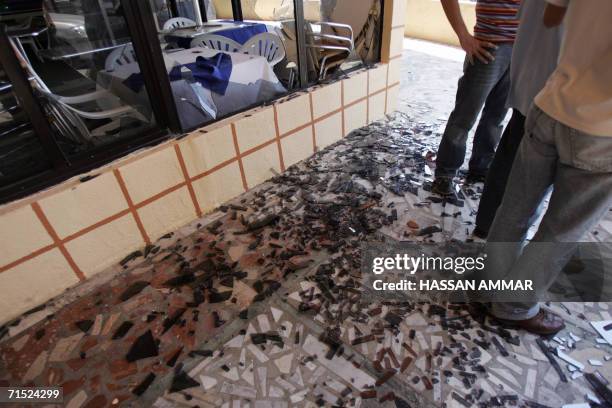 Lebanese men check a damaged shop after Israeli airstrikes hit a flat in the building in the southern Lebanese port city of Tyre, 27 July 2006....