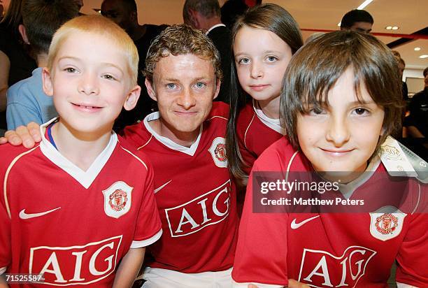 Ole Gunnar Solskjaer of Manchester United poses with three prize winners at the Official launch of the new Manchester United home kit in the...