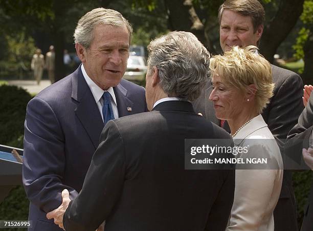 Washington, UNITED STATES: US President George W. Bush shakes hands with John Walsh as Walsh's wife Reve looks on, during the signing ceremony of...